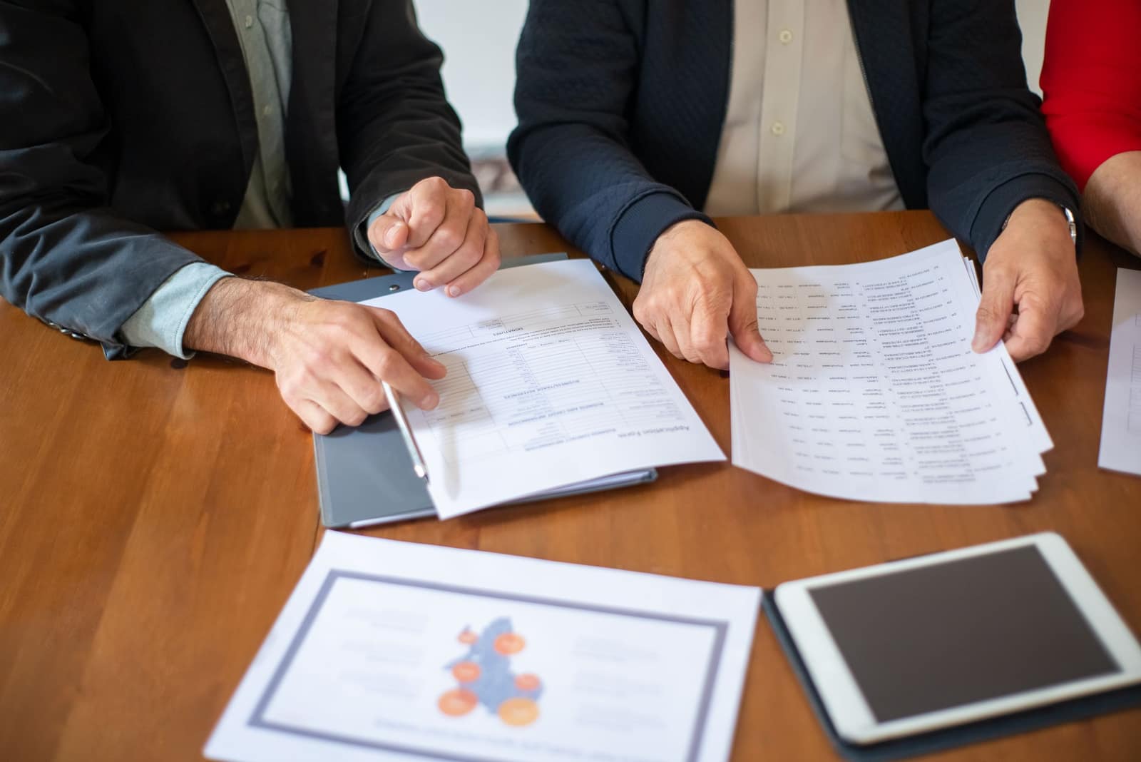 Two people reviewing printed tax documents and a return across a wooden table